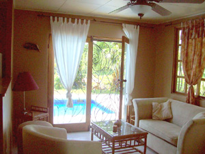 Through sliding doors with wrought iron screens, the pool can be seen outside the comfortably furnished living room.